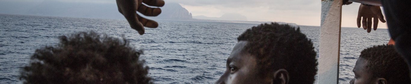 A bord du bateau Prudence, un groupe de migrants regarde les côtes siciliennes.