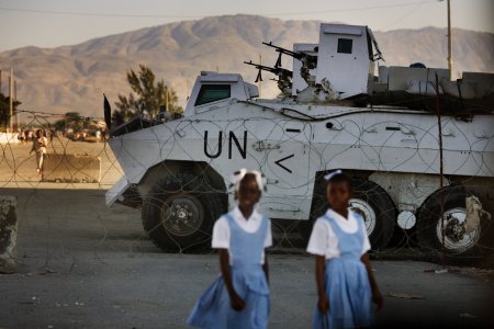 Two girls walk in front of a UN checkpoint in Haiti