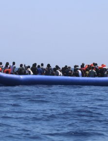 A group of people in distress in a rubber boat before being rescued.